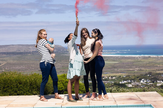Fototapeta Friends celebrating with smoke flare by poolside, enjoying scenic ocean view