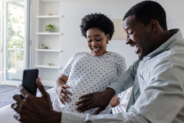 Expectant couple joyfully video calling family at home, sharing pregnancy news