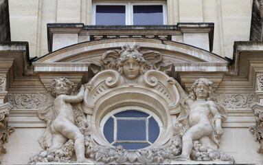Architectural fragments of the facade of ancient house in Paris- window decorated with floral bas relief ornament.
