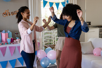 Friends celebrating at home, dancing joyfully with colorful balloons and decorations © WavebreakMediaMicro