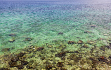 Transparent, crystal-clear emerald water with visible rocks. Koh Lipe, Thailand.