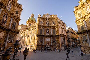 Obraz premium People stroll through Quattro Canti square in Palermo as golden light illuminates the baroque facades. This photo captures architectural elegance and the charm of urban exploration in Sicily