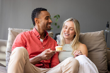 Couple celebrating birthday at home with cupcake and candle, sharing joyful moment