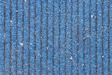 Dirty blue carpet with vertical lines lies on the street as a background