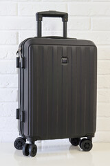 Black suitcase on white background. Vertical photo of black hand luggage for air travel.