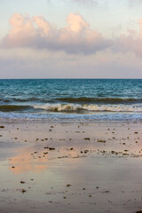 The pink clouds at sunset reflecting on the wet sand along a Mozambique beach.