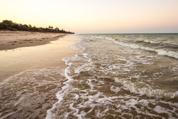 Surf on the deserted beach at Inhassoro in Mozambique at dusk.