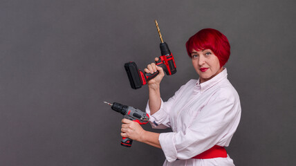 DIY enthusiast shows multitasking capability with dual screwdrivers. Red curls frame face as she...