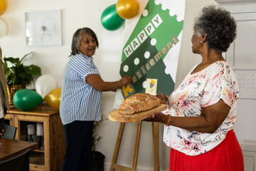 Women celebrating retirement at home with balloons and fresh bread