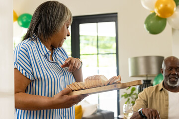 Obraz premium Woman serving sliced bread at home during festive family gathering