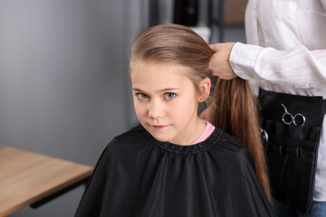 Fototapeta premium Hairdresser doing girl's hairstyle in salon, closeup