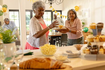 Senior women enjoying snacks at festive family gathering in bright living room