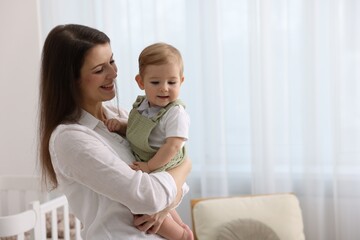 Mother with her cute little baby at home, space for text