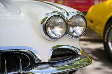 Front end of white vintage car with twin round headlights. Close-up of a white vintage car s front...