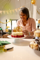 Smiling woman arranging cake decorations for 60th birthday celebration at home