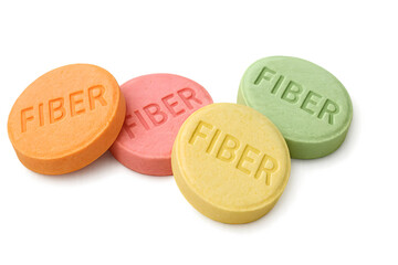 Four fiber supplement tablets in orange, pink, yellow, and green colors, each imprinted with the word FIBER. Concept Colorful Fiber Supplements, Tablet Imprints, Health Benefits of Fiber