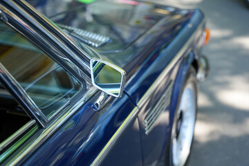 Blue vintage car mirror and fender. Close-up of a blue classic car s angular side mirror and front...