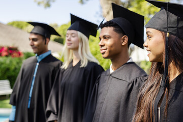 Graduating students outdoors in caps and gowns, celebrating academic achievement smiling