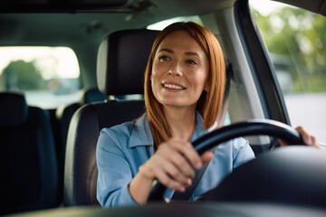Happy woman behind steering wheel on road trip.