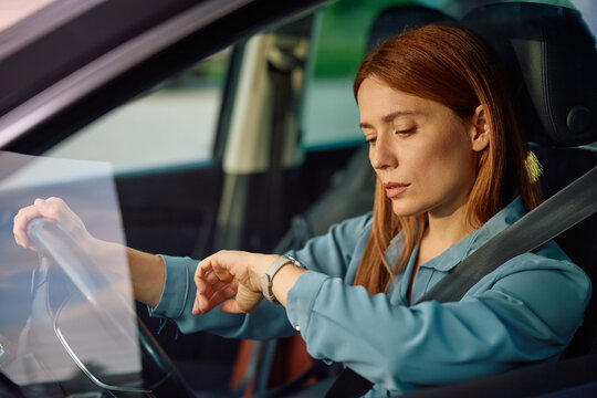 Businesswoman checking time on wristwatch while driving car.
