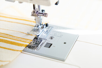 sewing machine with a cloth under a steel needle. manufacture of clothing. a household or industrial sewing machine. tailor, couturier. work on sewing designer clothes.