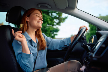 Carefree businesswoman listening music while commuting to work by car.