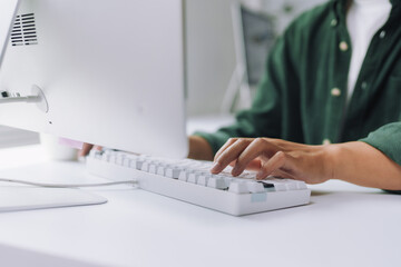 Close up of hands typing on white keyboard in modern office, developing innovative software solutions
