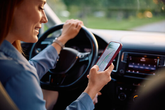 Close up of woman looking for direction on online map while driving car.