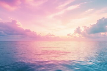 Obraz premium Peaceful sunset over calm ocean, soft pink and blue hues. Clouds fill the sky
