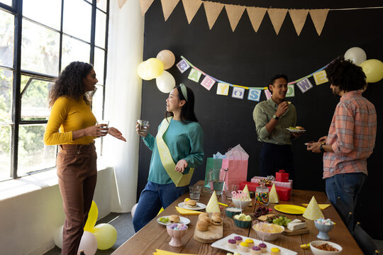 Colleagues enjoying baby shower celebration at office with snacks and decorations - Powered by Adobe