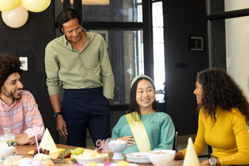 Diverse group celebrating baby shower at office, smiling and enjoying conversation
