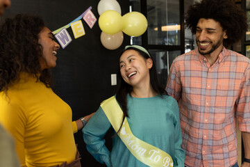 In office, colleagues celebrating baby shower, chatting and smiling together