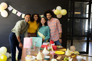 Diverse group celebrating baby shower with gifts and decorations in office