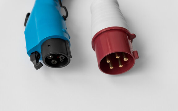 Type 1 and 5-pin industrial charging plugs. Close-up view of two types of charging plugs for electric vehicles. 