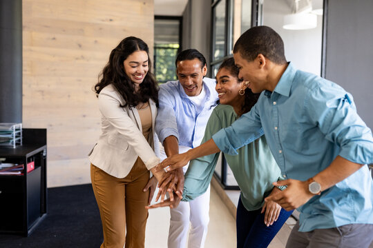 Diverse business team celebrating success with group high-five in modern office