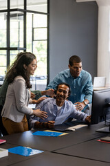 Fototapeta premium Collaborating around computer, team working together in modern office environment