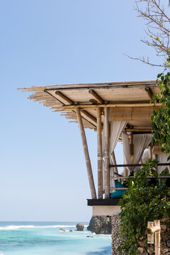 Tropical palapa open-air cabana elevated above ground with ocean views at a beach club in Bali, Indonesia. 