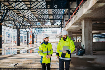 Engineers discussing construction plans using a tablet on site.