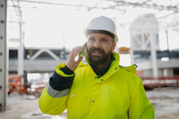 Portrait of construction foreman making phone call in modern building site.