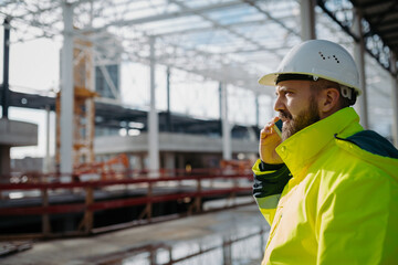 Portrait of construction foreman making phone call in modern building site.