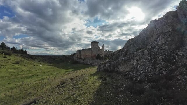 Ruins of rocca calascio castle emerging from the green valley under cloudy sky