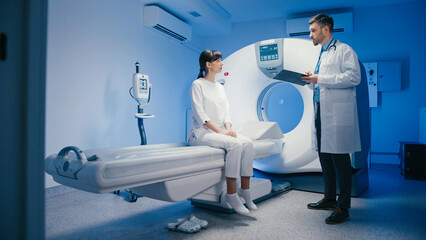 Caucasian woman in white clothing sitting near tomography machine and calmly waiting for...
