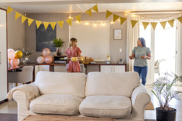 Women preparing for celebration at home, decorating with balloons and banners