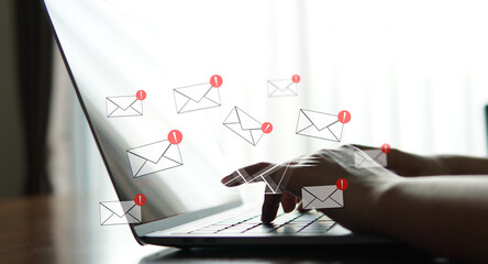 Business hand on keyboard of laptop with floating alert message inbox over laptop, email communication, inbox checking, and digital notification alert system.