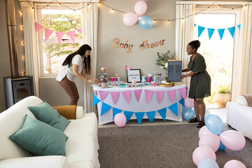 Decorating table for baby shower, two women arranging balloons and treats