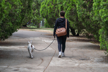 Mujer caminando por el parque junto a su perro