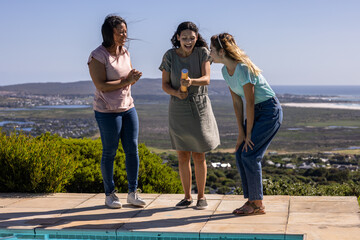 Friends celebrating by poolside with confetti popper, enjoying outdoor gathering