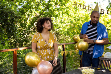 Fototapeta premium Friends decorating with balloons, celebrating birthday outdoors on sunny day