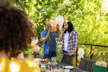 Celebrating outdoors, friends wearing party hats with balloons in festive atmosphere