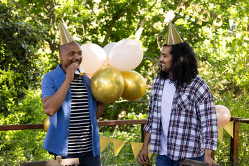 Friends celebrating outdoors wearing party hats and enjoying festive balloons